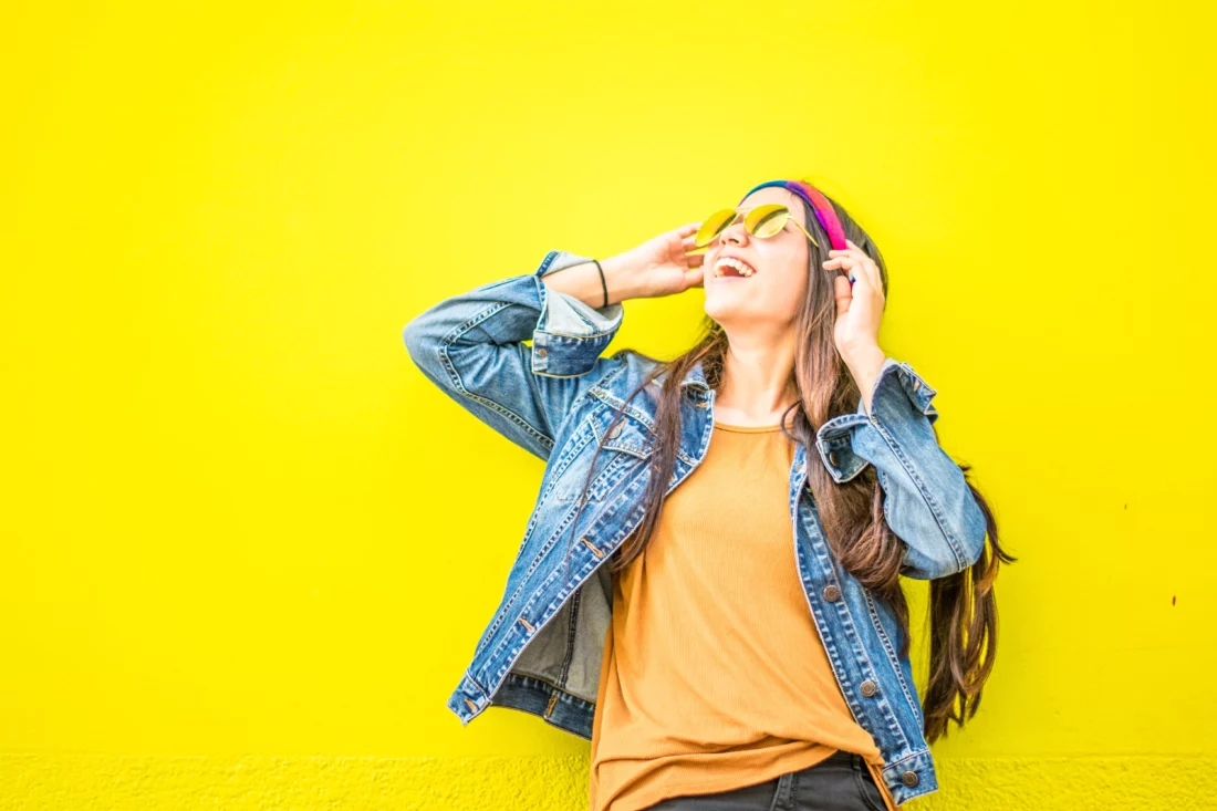 Woman smiling in front of a bright yellow background. Immediate Actions to Manage Alcohol Withdrawal Symptoms. Image by Juan Mendez @ Pexels.